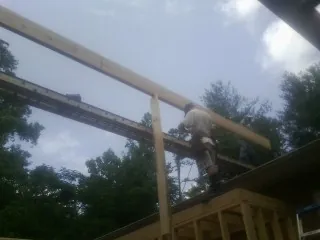 Carpenter setting a ridge beam over a new addition frame — Ice Dam Removal by Roofing Brothers in Farley