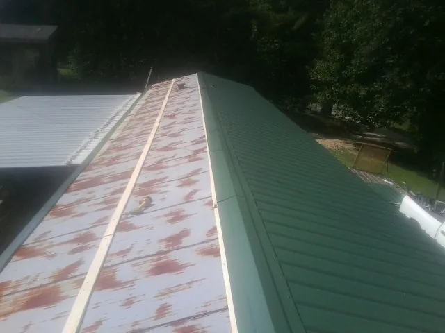 Old rusted panels beside newly installed green metal roofing — Wind Damage Roof Repair by Roofing Brothers in Farley
