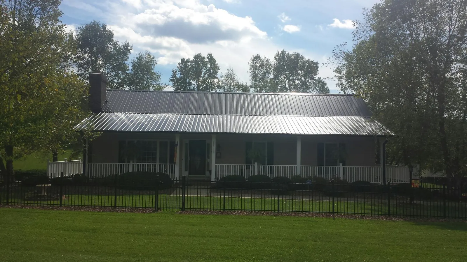 Gray metal roof on a brick ranch with a full width front porch — Gutter Guard Installation work by our crew in Farley